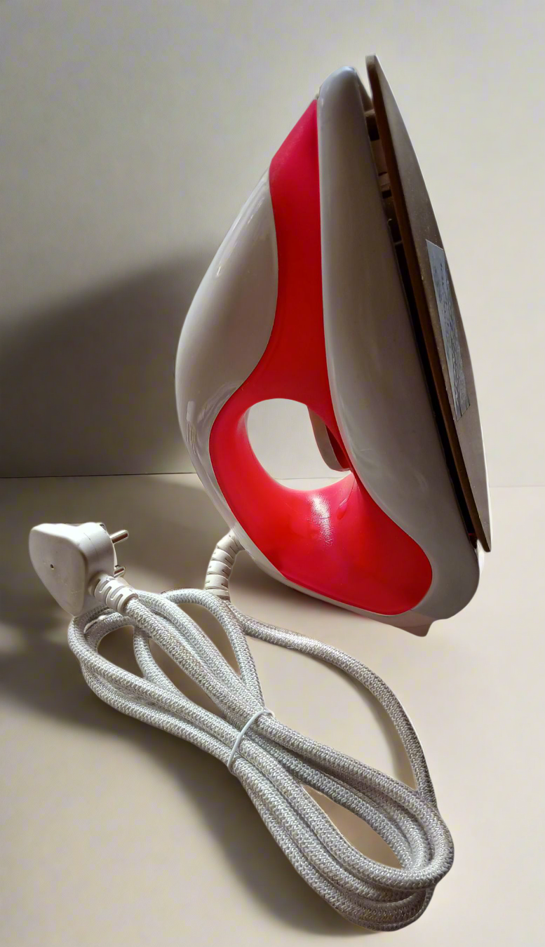 Red and gray iron with a white cord on a light background
